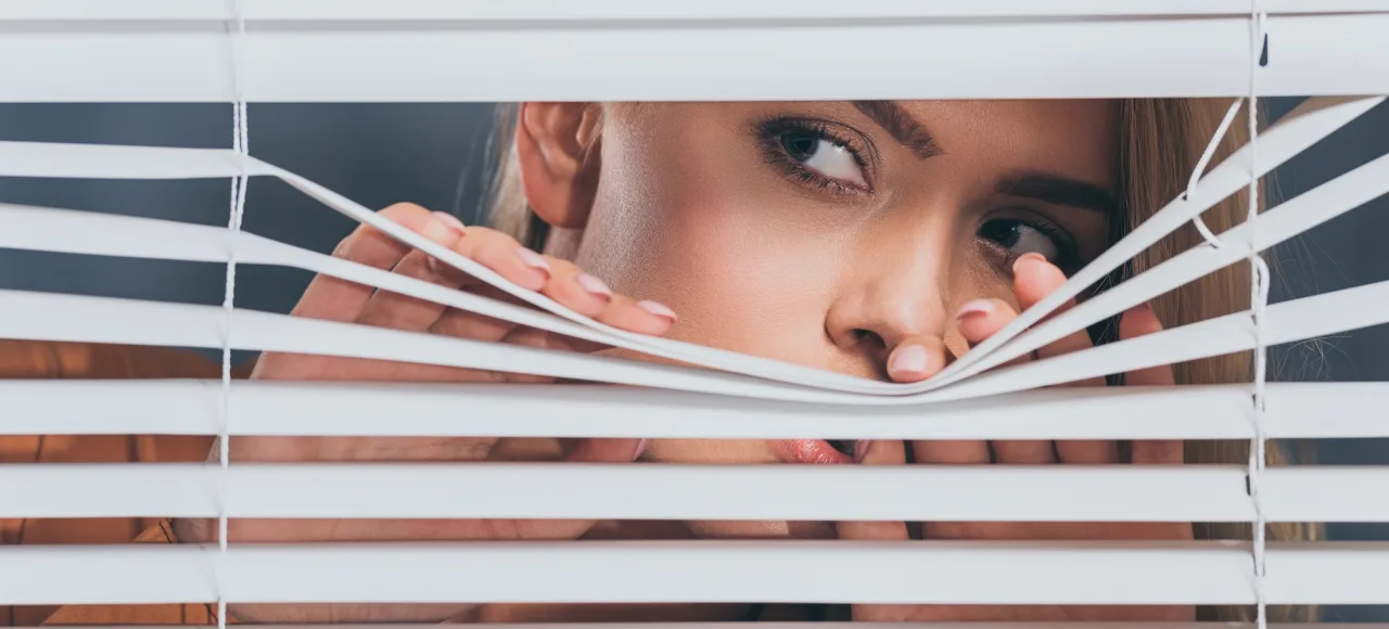 AdobeStock-woman-blinds-mistrust-suspicion-neighbours